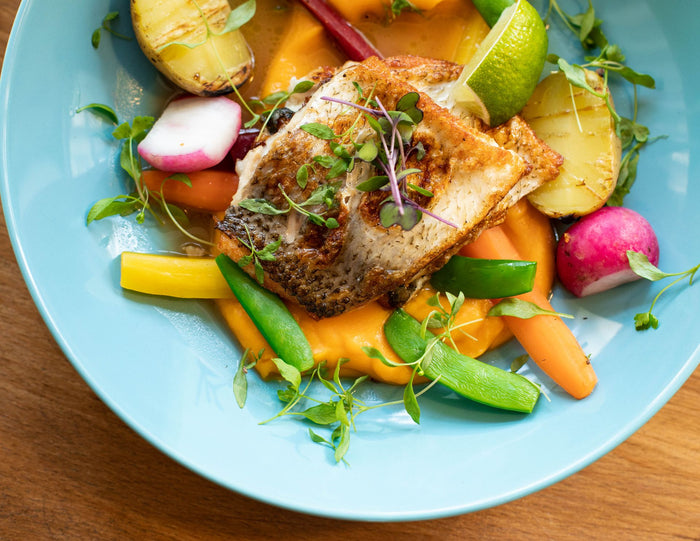 A seared fish fillet with fresh vegetables on a plate