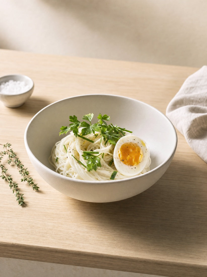 A clean breakfast bowl of egg white noodles with a soft-boiled egg