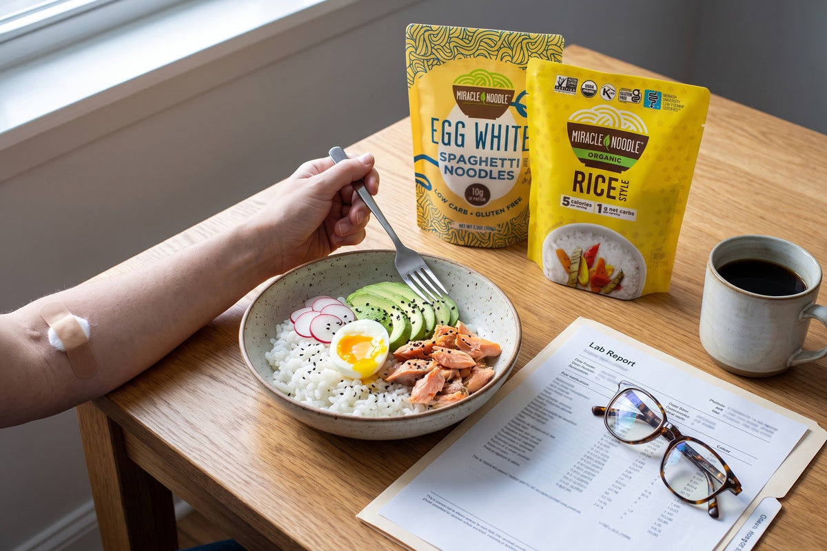 A forearm with a small bandage beside a rice bowl with a soft egg, trout and avocado, a lab report and glasses, with Miracle Noodle Egg White Spaghetti and Rice pouches