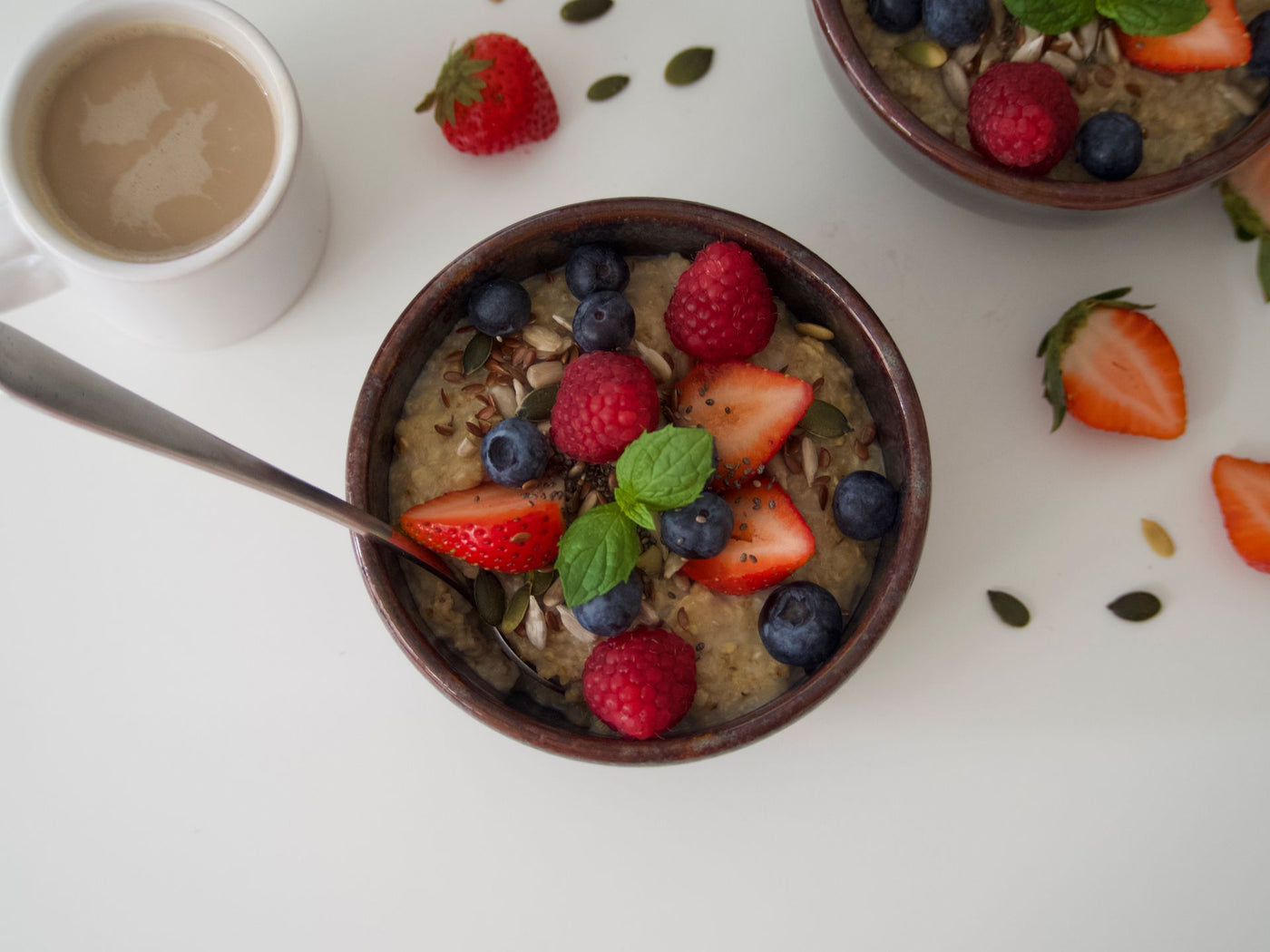 A bowl of oatmeal topped with fresh berries and seeds, seen from above