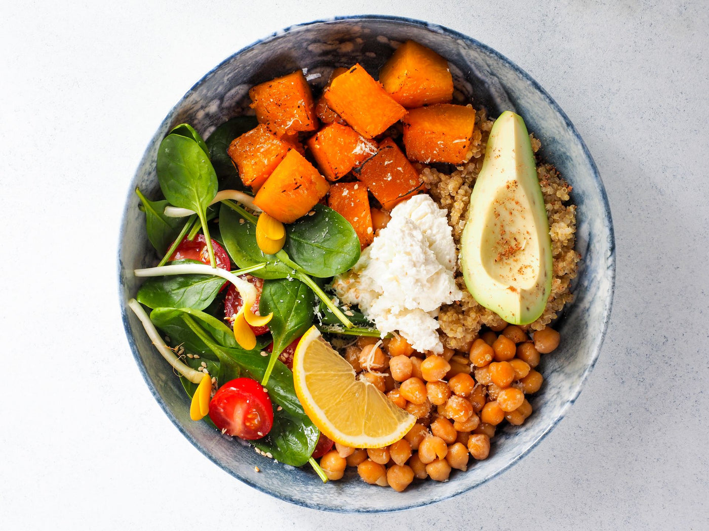 A balanced bowl of roasted squash, greens, chickpeas, quinoa and avocado